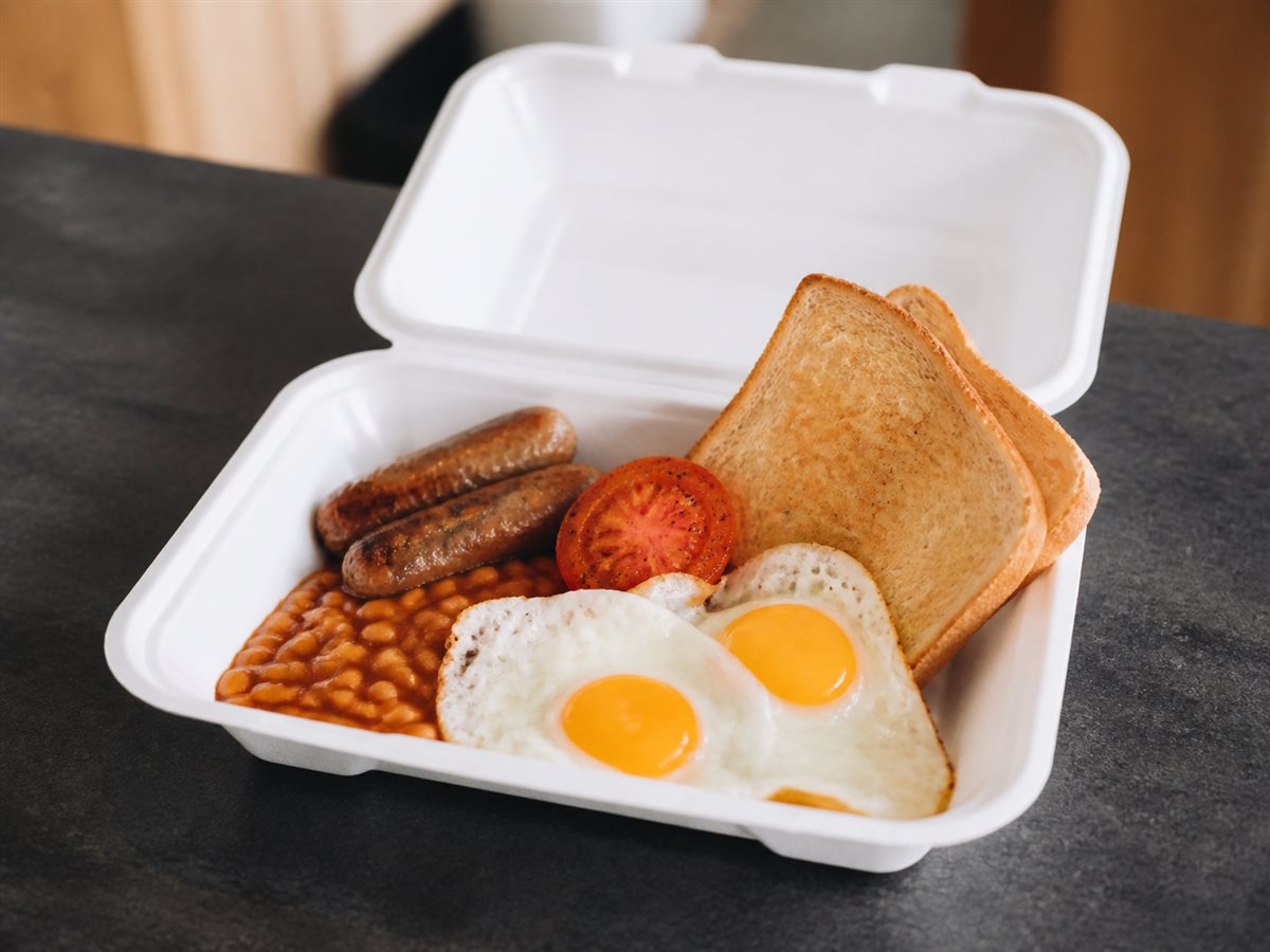 Eggs, toast, sausages, beans and tomato in a takeaway breakfast container